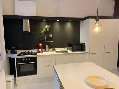 a kitchen with white cabinets and a stove top oven at Loft St Remacle in Liège