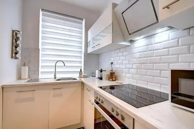 a kitchen with white cabinets and a sink and a fireplace at - Le Cocoune - Cosy & Cute Flat in Liège