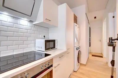 a white kitchen with a microwave and a refrigerator at - Le Cocoune - Cosy & Cute Flat in Liège