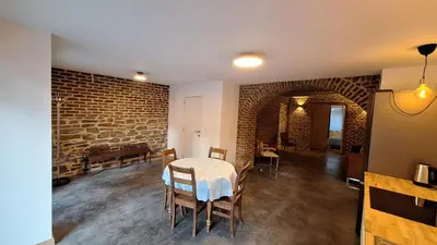 a dining room with a table and chairs and a brick wall at Bed and breakfast Le fourchu fossé in Liège
