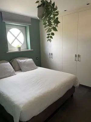 a bedroom with a large white bed with a window at Aurelia Glamping en B&B in Lommel
