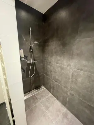 a bathroom with a shower with gray tiles at Aurelia Glamping en B&B in Lommel