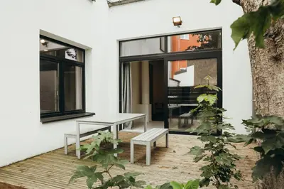 a patio with a bench and a table and windows at La Terrasse des Guillemins by WelcHome in Liège