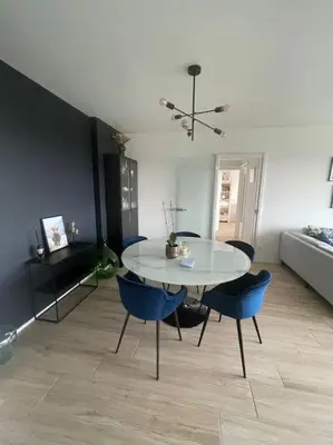 a dining room with a white table and blue chairs at Appartement panoramique plein sud Liège in Liège