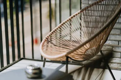 a wicker chair sitting on a balcony next to a fence at 2 bedroom apartment and private parking in Liège center in Liège