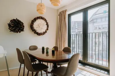 a dining room with a table and chairs and a large window at 2 bedroom apartment and private parking in Liège center in Liège