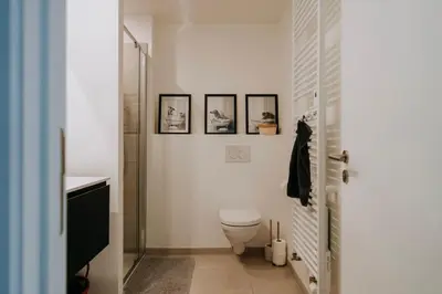 a bathroom with a toilet and three pictures on the wall at 2 bedroom apartment and private parking in Liège center in Liège