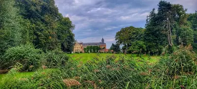 a large building in the middle of a green field at Hoeve Hofgaarde in Heers