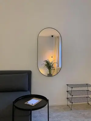 a living room with a black couch and a mirror at 2 bedroom duplex in the historic heart of Liège in Liège