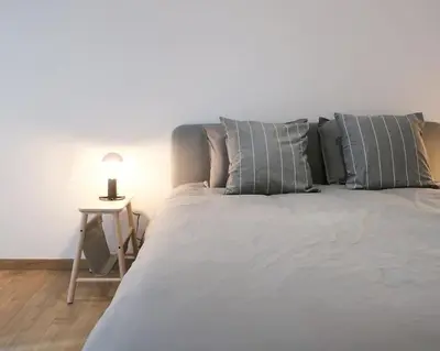 a large white bed with pillows and a table at 1 bedroom apartment in Liège center - 1st floor in Liège