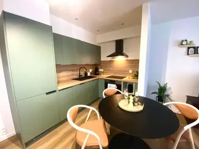 a kitchen with a black table and chairs at Le cozy escape in Herstal