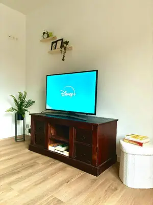 a flat screen tv sitting on top of a wooden entertainment center at Le cozy escape in Herstal