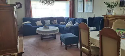 a living room with a blue couch and a table at A home away from home in Oudsbergen