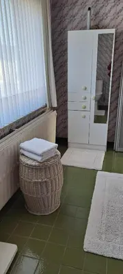a bathroom with a basket and a dresser and a mirror at A home away from home in Oudsbergen