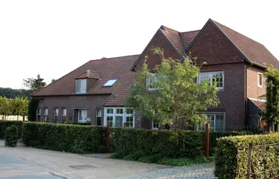 a brick house with a hedge in front of it at B&B Het Welthof in Bree