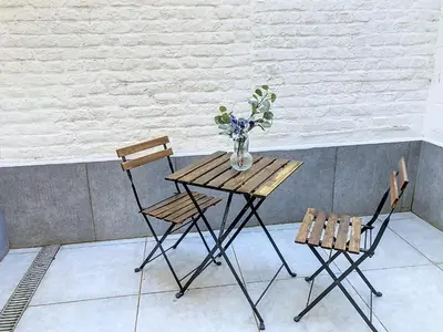 a wooden table with two chairs and a vase with flowers at Angleur Appartement 001 rez arrière in Liège