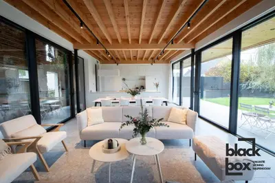 a living room with couches and tables and windows at Black Box by De Schrijfbar - vakantiewoning Haspengouw in Wellen