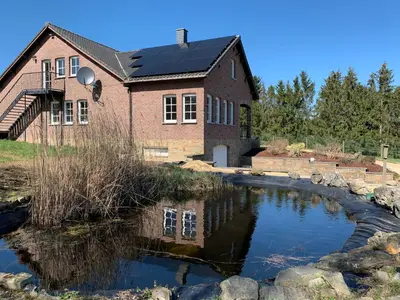 a house with a pond in front of it at Eaglenest in Baelen