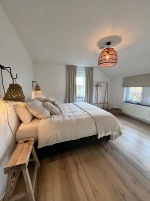 a bedroom with a large bed with a wooden floor at De Boomgaard Voeren in Voeren