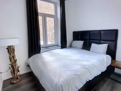a bedroom with a bed with a black headboard and a window at Angleur Appartement 011 1er étage avant cosy in Liège