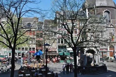 a group of people sitting at tables in front of a building at Angleur Appartement 011 1er étage avant cosy in Liège