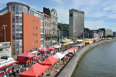 a group of restaurants with red and white umbrellas next to a river at Angleur Appartement 011 1er étage avant cosy in Liège
