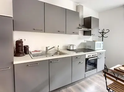 a white kitchen with a sink and a microwave at Angleur Appartement 011 1er étage avant cosy in Liège