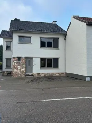 a white house with a parking lot next to a street at La Redoute in Tongeren