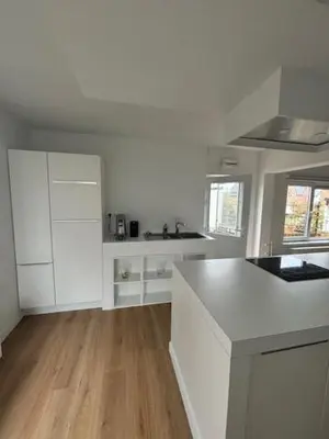 a kitchen with white cabinets and a wooden floor at La Redoute in Tongeren