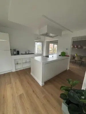 a large kitchen with white cabinets and a wooden floor at La Redoute in Tongeren