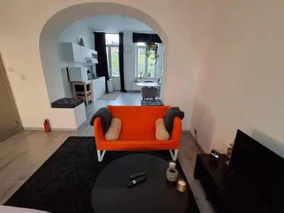 a living room with an orange couch and a table at La Vie en Rose in Verviers