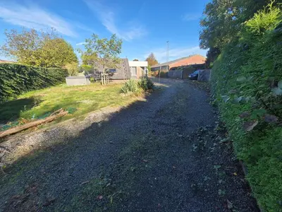 a gravel road next to a yard with a house at Afgelegen woning met buitenjacuzzi en vergaderruimte ! in Pelt