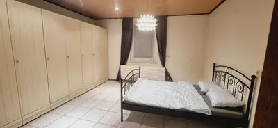 a bedroom with a bed and a window and a chandelier at Afgelegen woning met buitenjacuzzi en vergaderruimte ! in Pelt