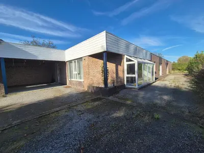 a brick building with a white roof at Afgelegen woning met buitenjacuzzi en vergaderruimte ! in Pelt