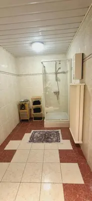a bathroom with a shower and a tiled floor at Afgelegen woning met buitenjacuzzi en vergaderruimte ! in Pelt