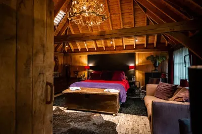 a bedroom with a bed and a couch and a chandelier at Het Zwart Schaap in Pelt