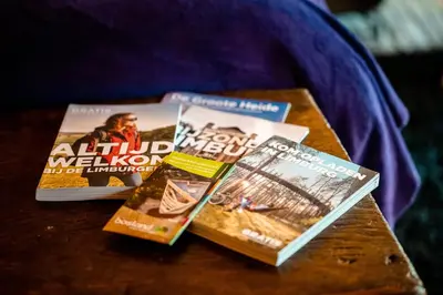 three magazines sitting on a wooden table at Het Zwart Schaap in Pelt