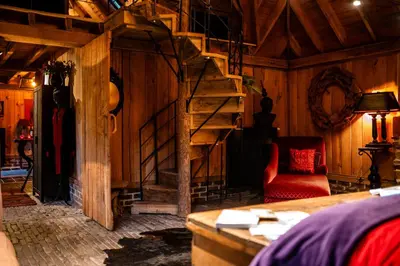 a living room with a spiral staircase and a red chair at Het Zwart Schaap in Pelt