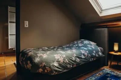 a bedroom with a bed with a floral blanket at L'Air du Pré by WelcHome in Verviers