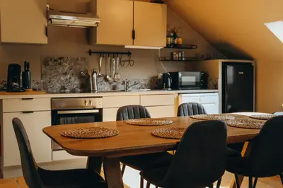 a kitchen with a wooden table and chairs at L'Air du Pré by WelcHome in Verviers