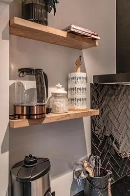 a kitchen with wooden shelves with pots and pans at Villa Victoire in Heers
