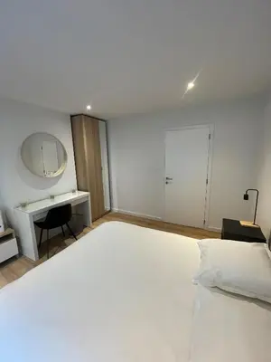 a bedroom with a large white bed and a desk at Magnifique appartement 1 chambre in Liège