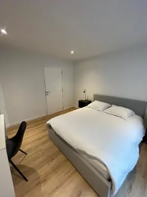 a bedroom with a large white bed and a chair at Magnifique appartement 1 chambre in Liège