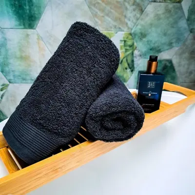 a black towel sitting on a wooden shelf with a bottle at Chambre et salle de bain privative in Liège