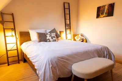 a bedroom with a bed with a chair and a ladder at Broekemmolen - Nature getaway & green spot in Bilzen