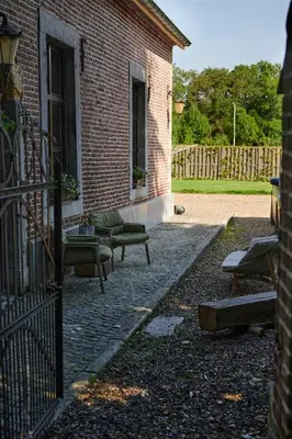 a patio with couches and a fence next to a building at Broekemmolen - Nature getaway & green spot in Bilzen