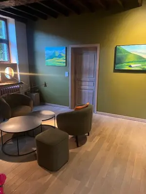 a room with chairs and tables and a painting on the wall at Broekemmolen - Nature getaway & green spot in Bilzen