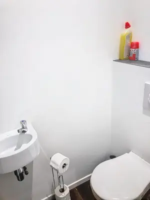 a white bathroom with a toilet and a sink at Appartement 002 au rez-de-chaussée avant in Angleur