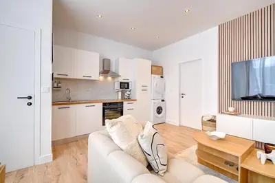 a white living room with a couch and a table at - Suite Solvay - Cosy & Modern Flat in Liège
