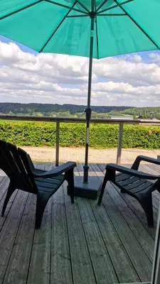 two chairs and an umbrella on a wooden deck at Chalet nr 17 Park Bergzicht Teuven in Voeren